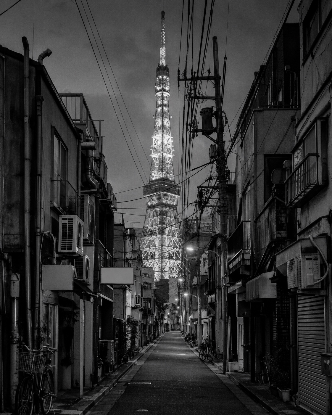 東京の路地。電線の張り巡らされた街並みの先に東京タワー